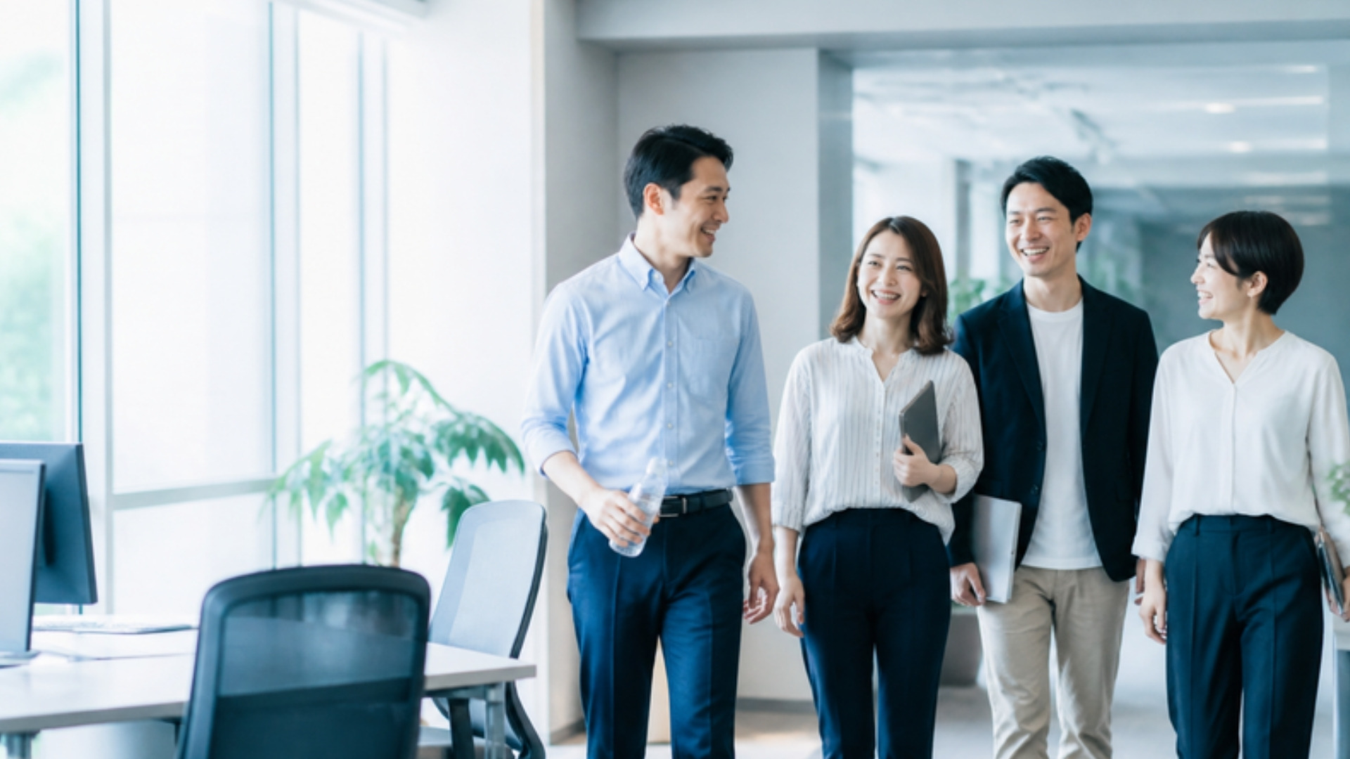 明るいオフィスを談笑しながら歩く社員たち