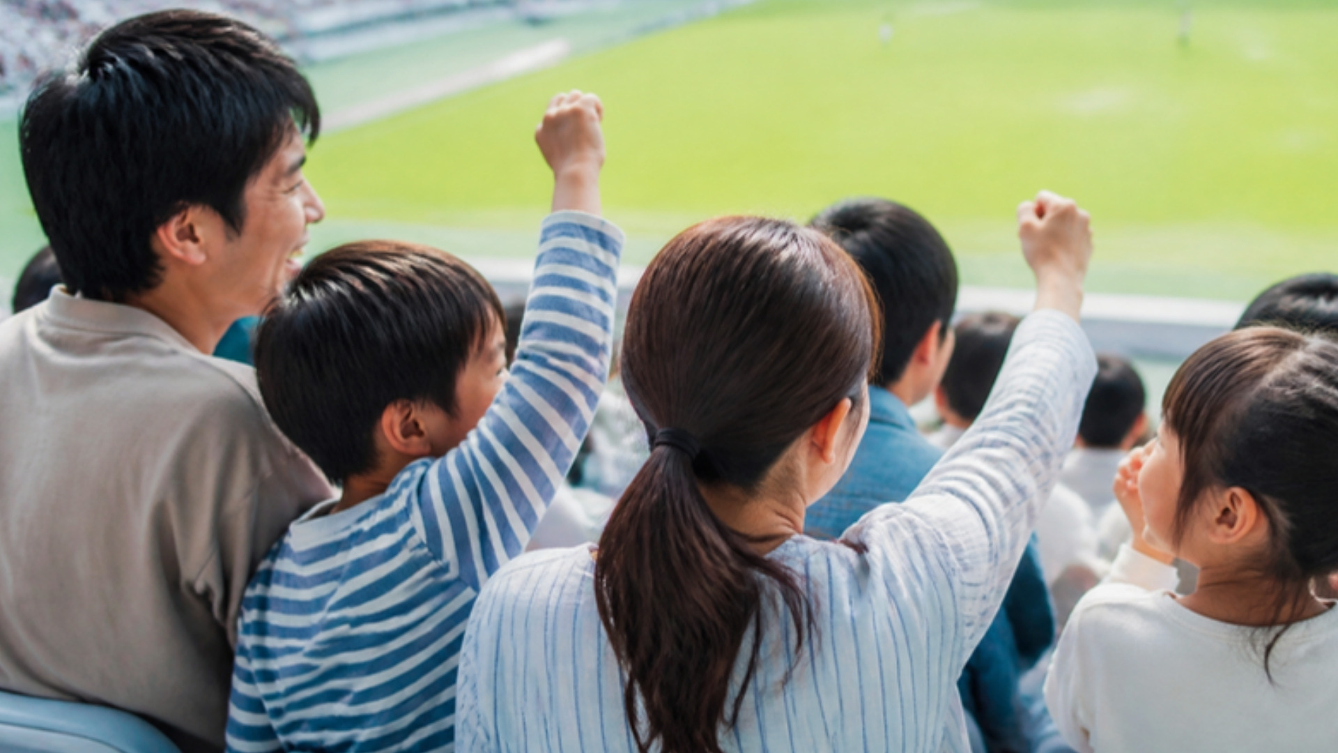 スタジアムで家族と一緒に応援する人々